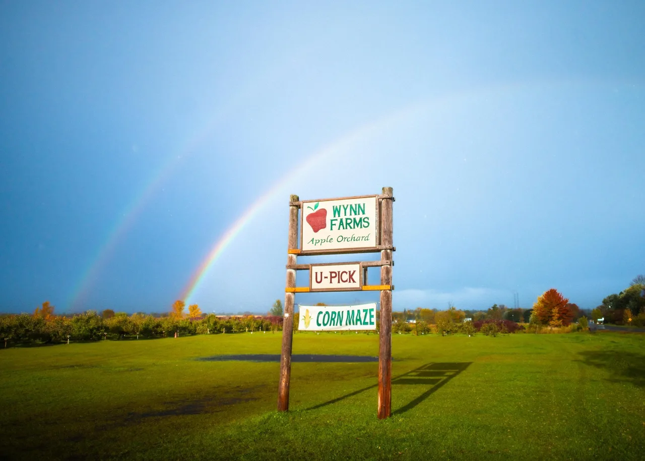 Wynn Farms orchard sign beneath a double rainbow